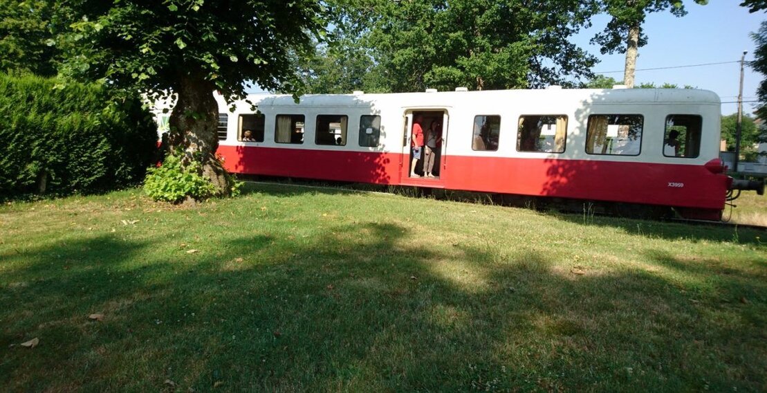 Un wagon de train rouge et blanc stationné sur une voie ferrée, prêt à partir.